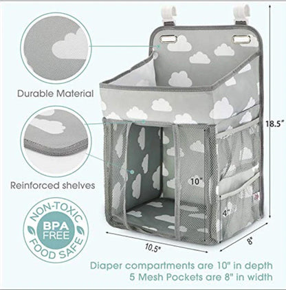A gray crib-side organizer hanging on a white crib, storing various baby items like diapers, bottles, and toys.