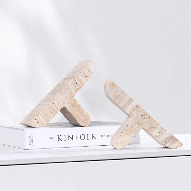 Elegant beige travertine stone bookends providing stable support for books and decor on a wooden shelf