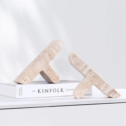 Elegant beige travertine stone bookends providing stable support for books and decor on a wooden shelf