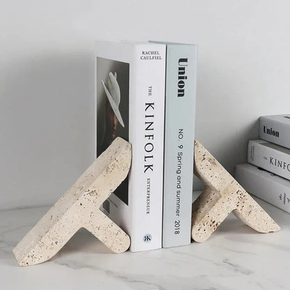 Elegant beige travertine stone bookends providing stable support for books and decor on a wooden shelf