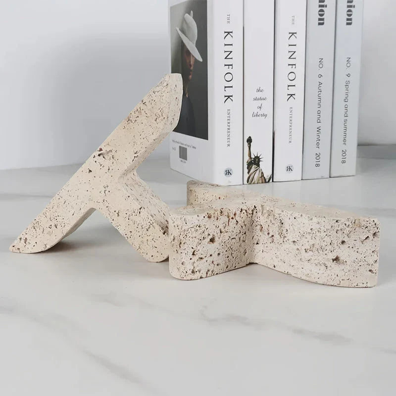 Elegant beige travertine stone bookends providing stable support for books and decor on a wooden shelf