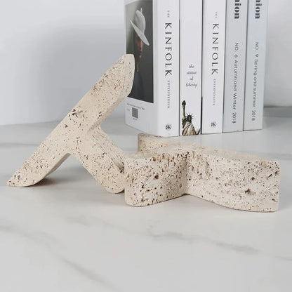 Elegant beige travertine stone bookends providing stable support for books and decor on a wooden shelf
