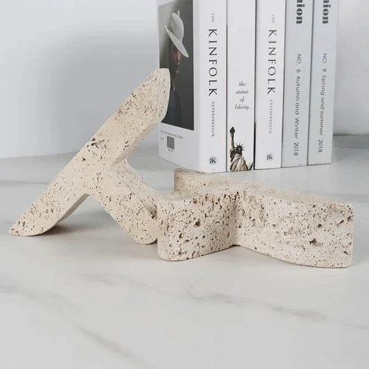 Elegant beige travertine stone bookends providing stable support for books and decor on a wooden shelf