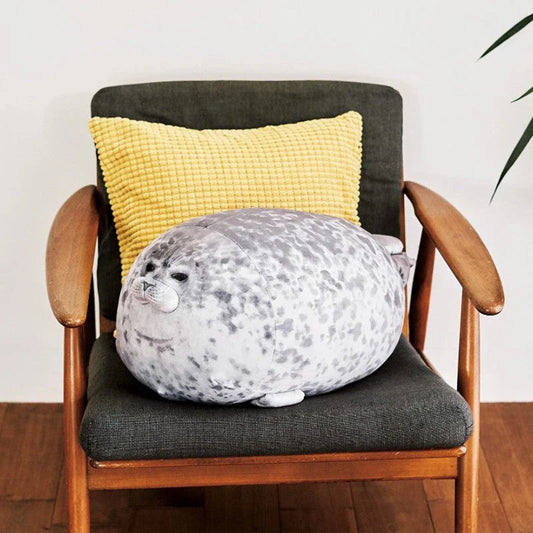 A plush, soft, and cuddly grey or white seal-shaped cushion with a detailed, lifelike design