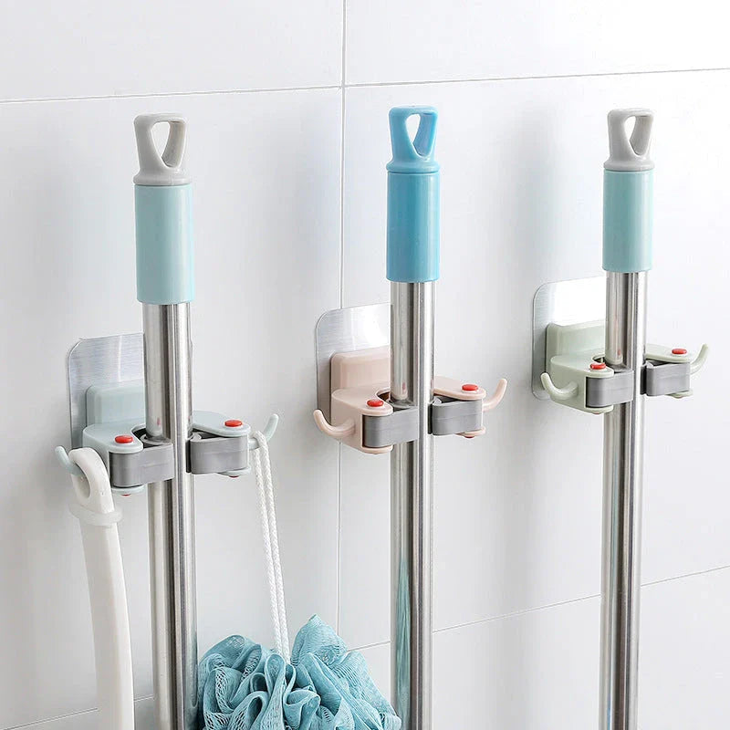 Adhesive wall-mounted mop and broom holder with double hooks for storing cleaning tools, available in multiple colors.
