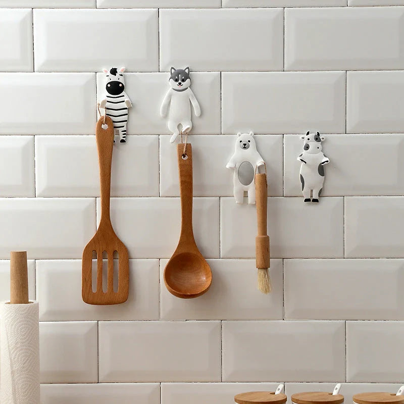 Assorted animal-shaped wall hooks in various colours, including bear, zebra, and cow designs, displayed on a white background