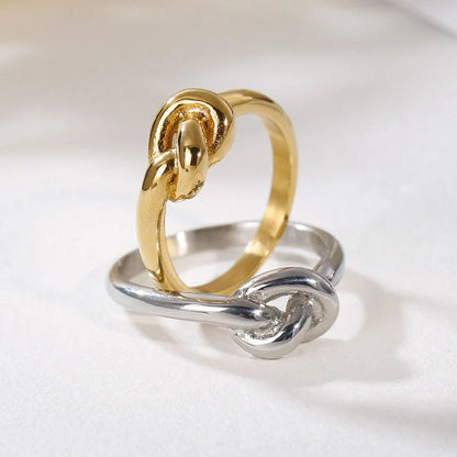 Sleek titanium steel geometric love knot ring in golden and rose gold colours, showcasing a modern and sophisticated design