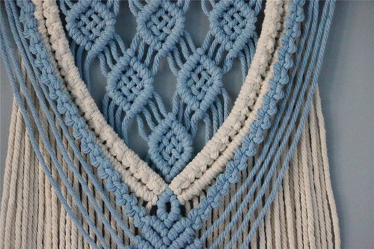 Hand-woven cotton string tapestry with blue and white colours, featuring playful tassels for a modern and rustic wall decoration