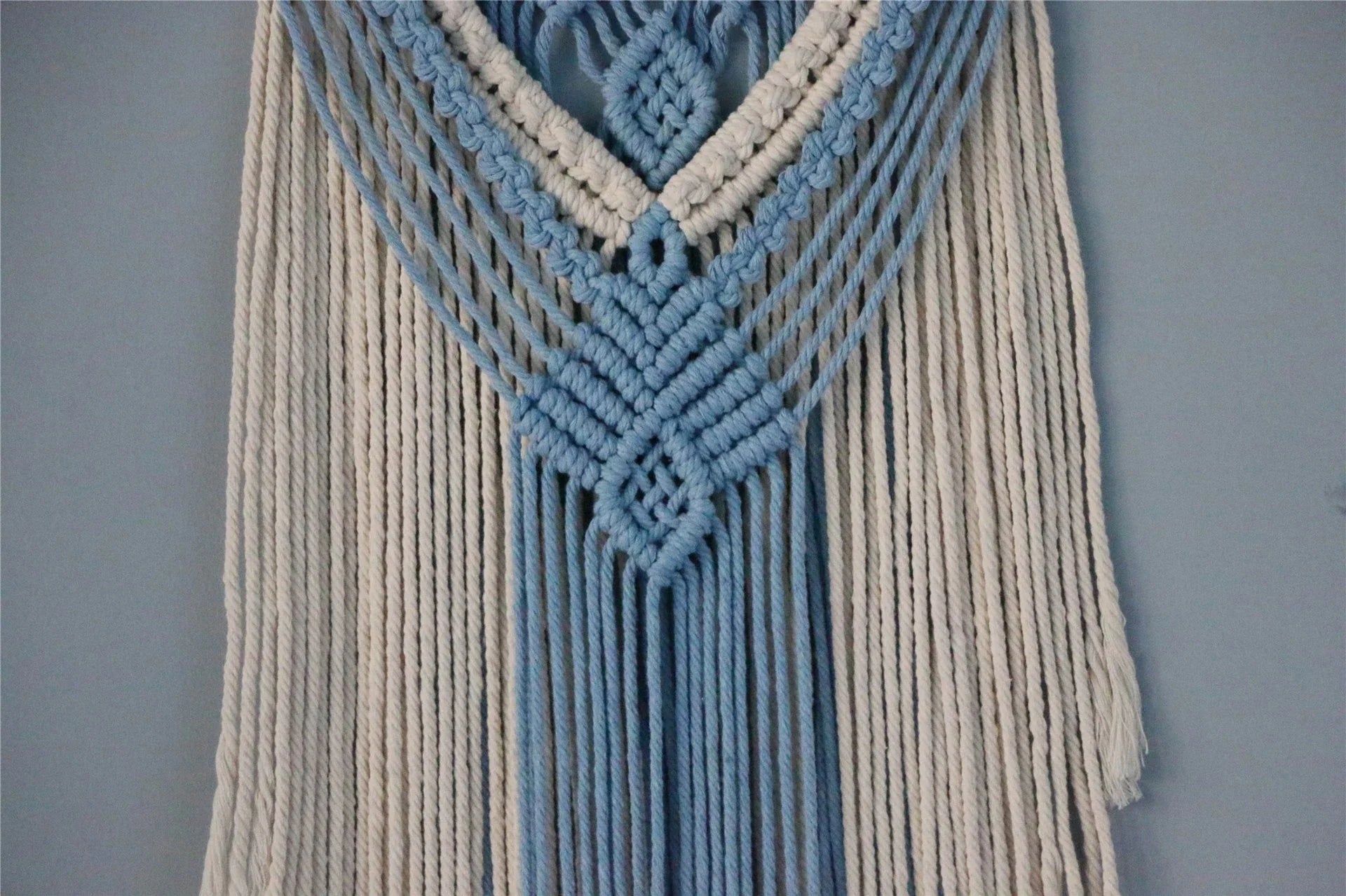 Hand-woven cotton string tapestry with blue and white colours, featuring playful tassels for a modern and rustic wall decoration