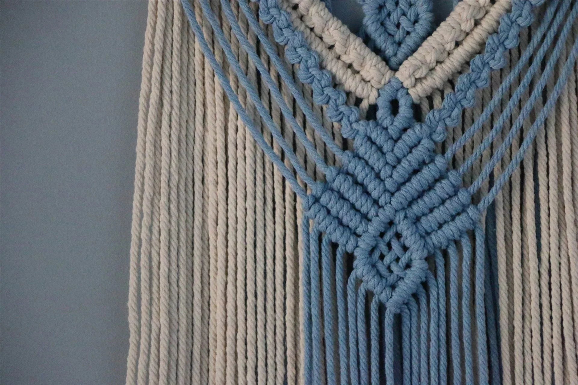 Hand-woven cotton string tapestry with blue and white colours, featuring playful tassels for a modern and rustic wall decoration