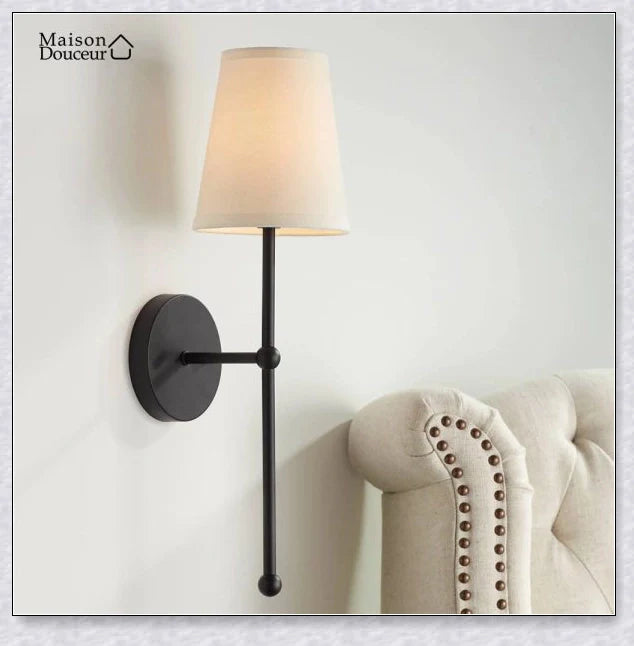 A modern, black and white wireless wall lamp with a fabric shade, providing elegant lighting for a living room or bedroom.