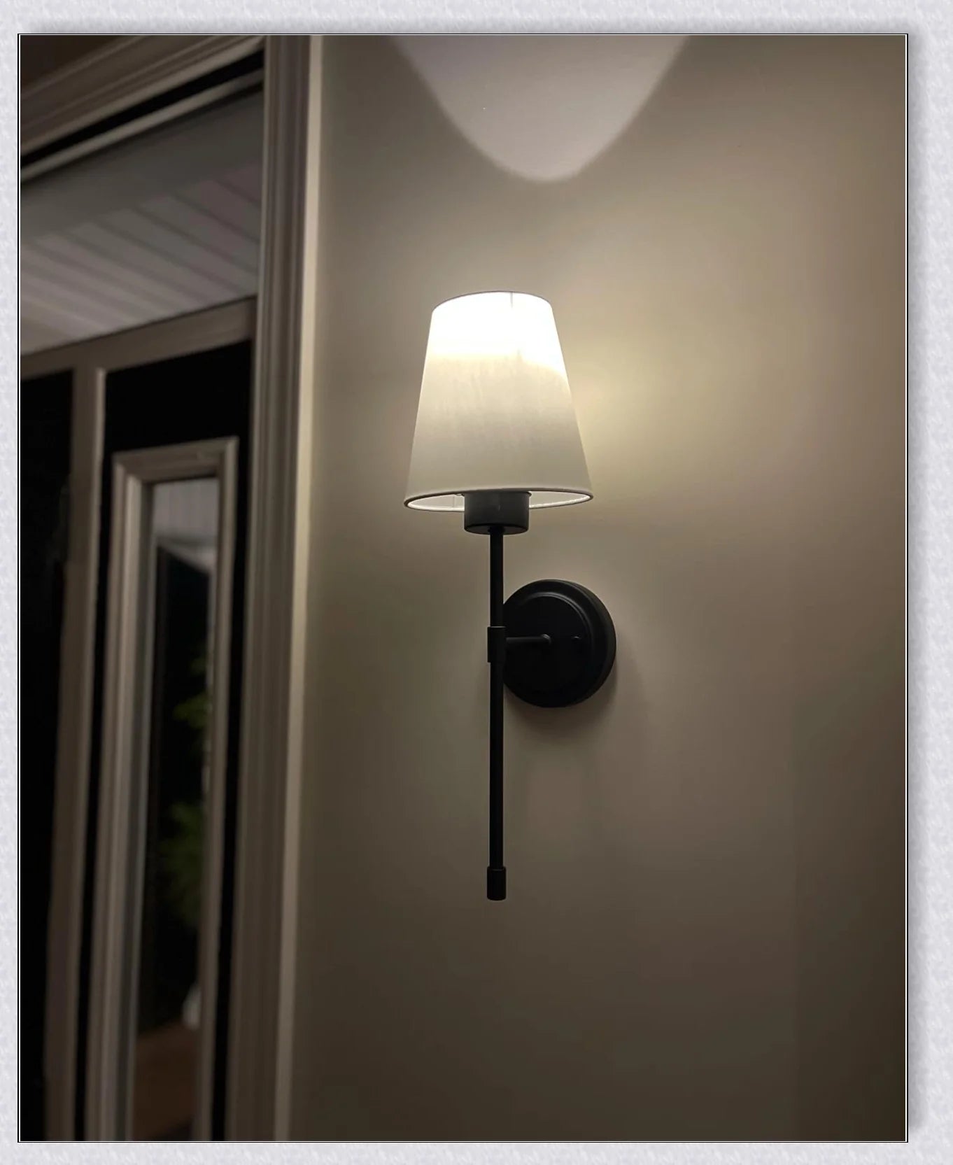 A modern, black and white wireless wall lamp with a fabric shade, providing elegant lighting for a living room or bedroom.