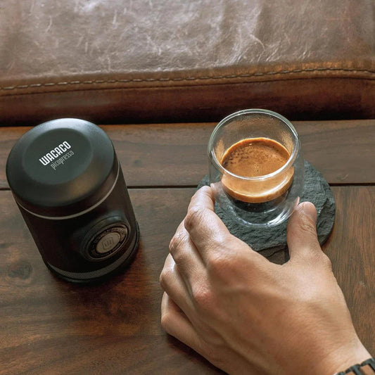 Portable espresso maker with a sleek black design, featuring a naked portafilter and manual operation for crafting premium coffee on the go.