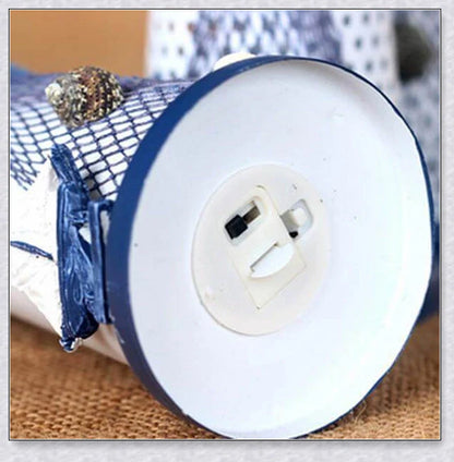 Oceanica LED Lighthouse Lantern Nightlight with nautical details like a small boat, life buoy, and seashells, providing a soft warm glow.