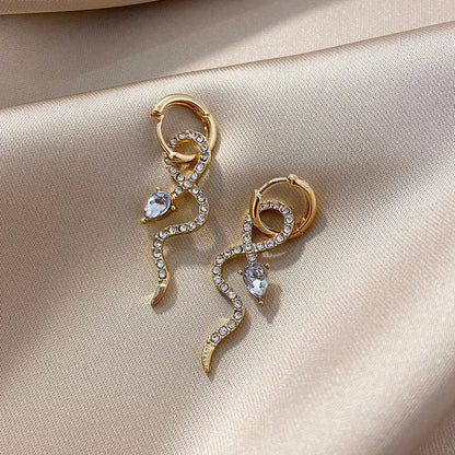 Elegant gold-toned snake charm earrings with a dangle design, perfect for adding a touch of sophistication to any outfit.