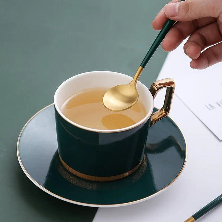 A set of minimalist, eco-friendly tableware in green and gold tones, including plates, bowls, and utensils.