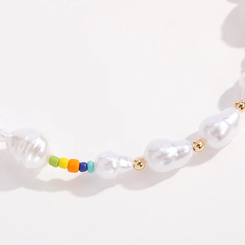A close-up view of a gold-plated multi-strand necklace featuring delicate imitation pearls arranged in a geometric pattern.