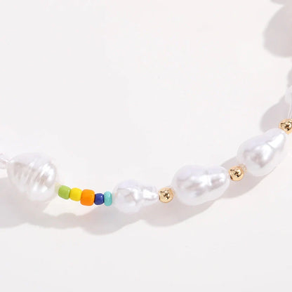 A close-up view of a gold-plated multi-strand necklace featuring delicate imitation pearls arranged in a geometric pattern.