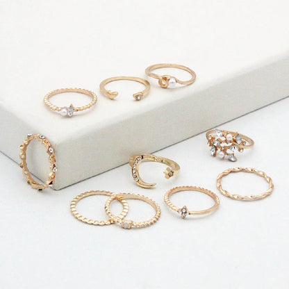 A set of 10 adjustable gold-plated rings with celestial-inspired designs including moons, stars, and pearls