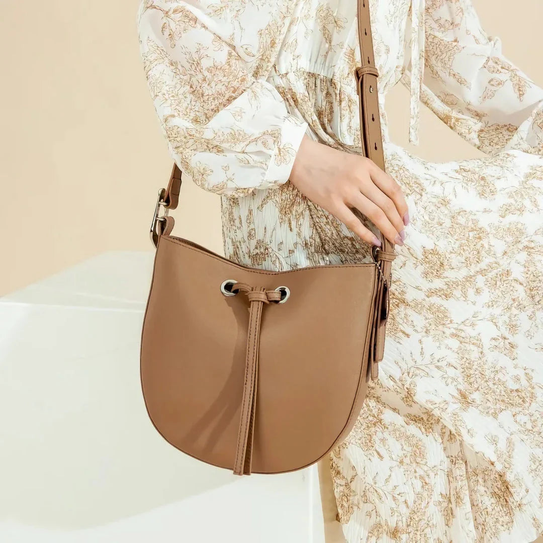 Elegant black leather bucket handbag with a metal buckle detail and adjustable strap
