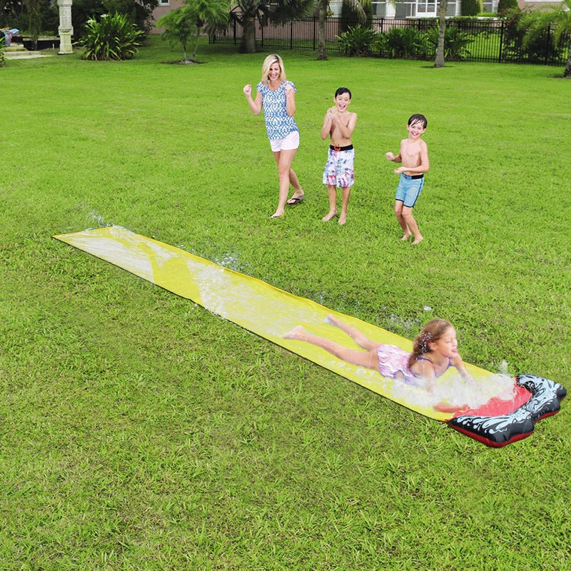 Kids playing on a yellow inflatable water slide in a backyard garden setting