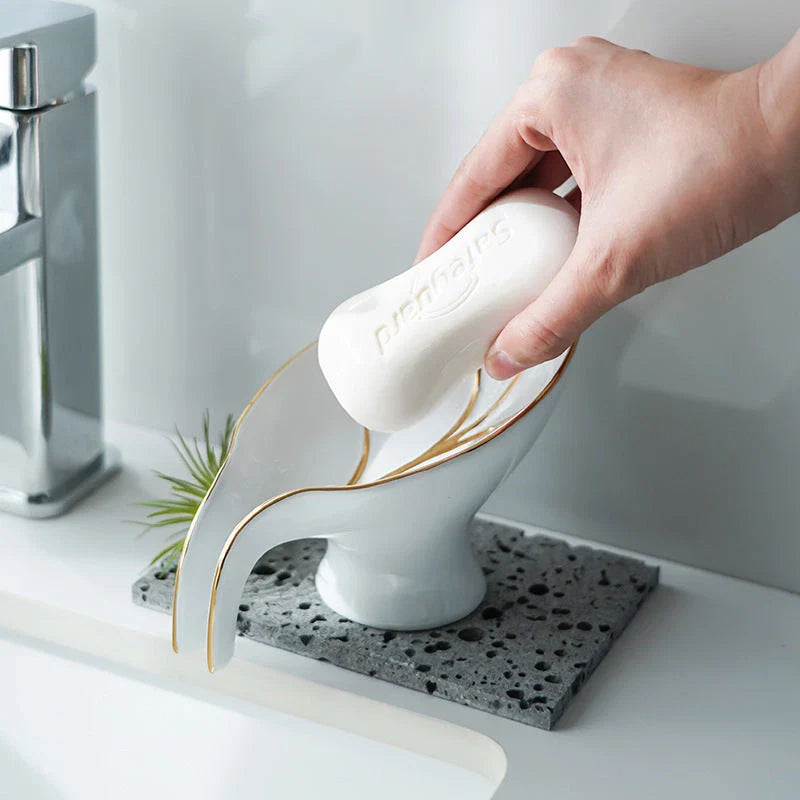 Elegant ceramic soap dish with leaf-shaped design, suction cup base, and drainage holes for bathroom storage and decor
