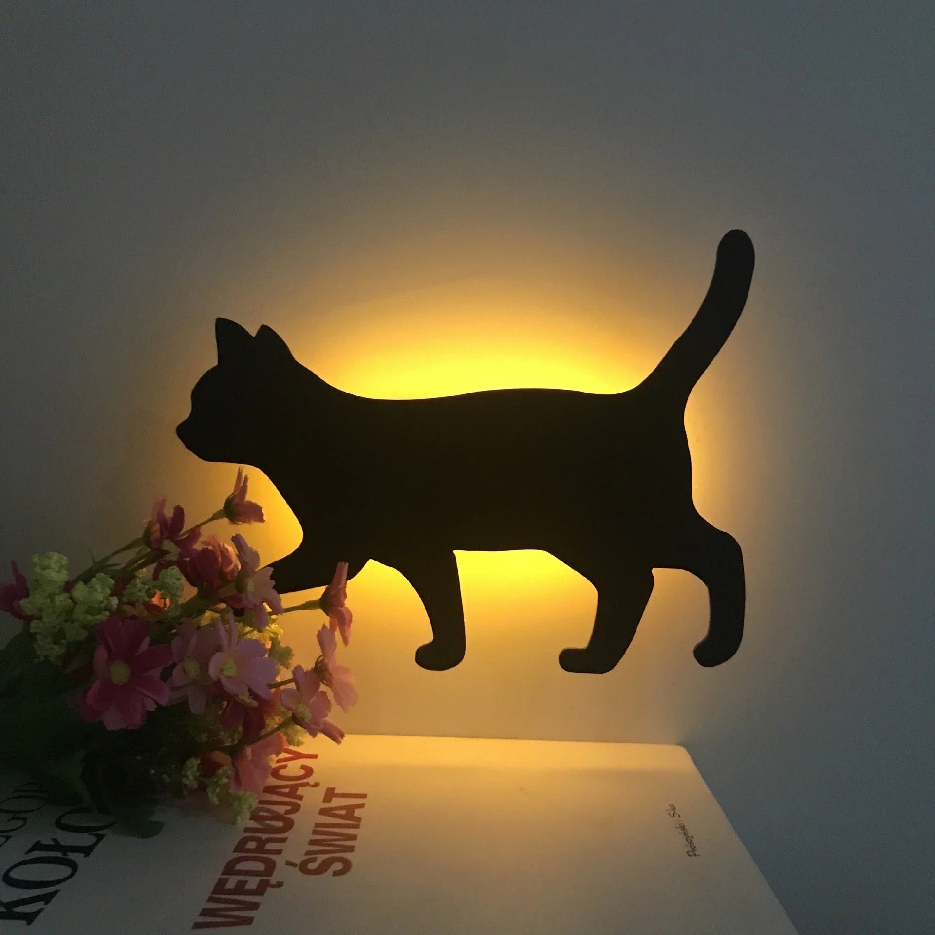 A stylish cat-shaped smart sensor night light that automatically illuminates a room when motion is detected, creating a warm and cozy atmosphere.