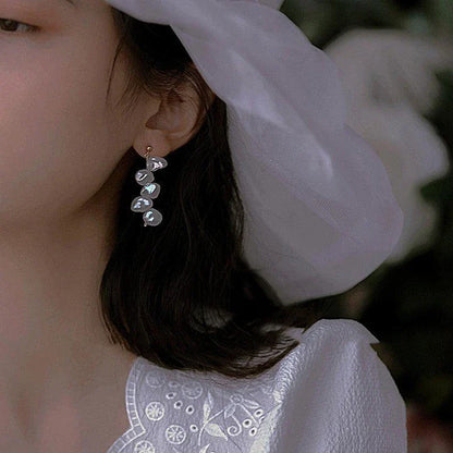 Pair of natural baroque pearl earrings with spiral clip design, featuring uniquely formed pearls in a shimmering display