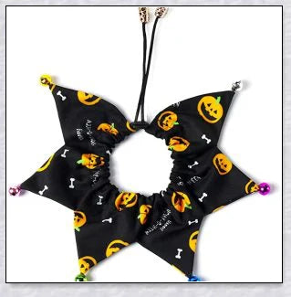 A cat wearing a Halloween costume set with a pumpkin and spider pattern hat and a collar with jingle bells.