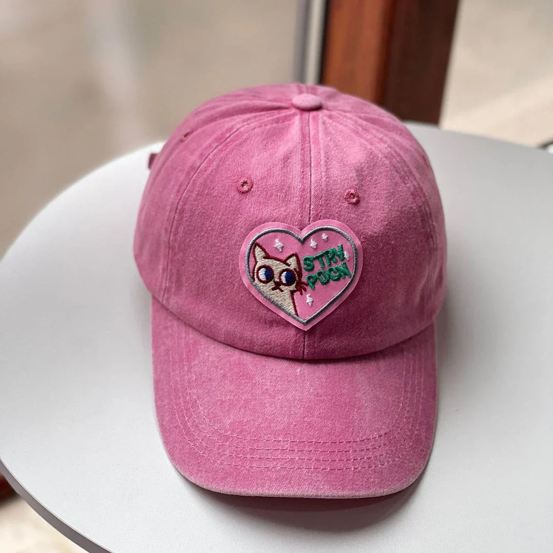 Two pink baseball caps with a cartoon love design, perfect for both women and men to add a touch of playful personality to their outfits.