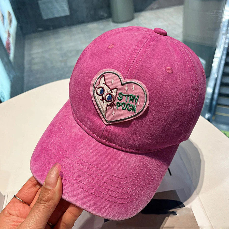 Two pink baseball caps with a cartoon love design, perfect for both women and men to add a touch of playful personality to their outfits.