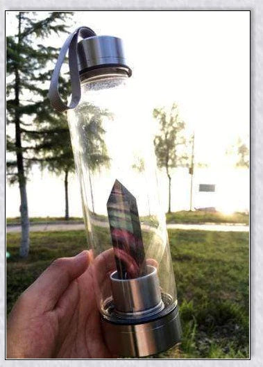 A natural crystal water bottle made of borosilicate glass, featuring a variety of healing crystals inside to enhance your hydration experience.
