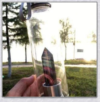 A natural crystal water bottle made of borosilicate glass, featuring a variety of healing crystals inside to enhance your hydration experience.