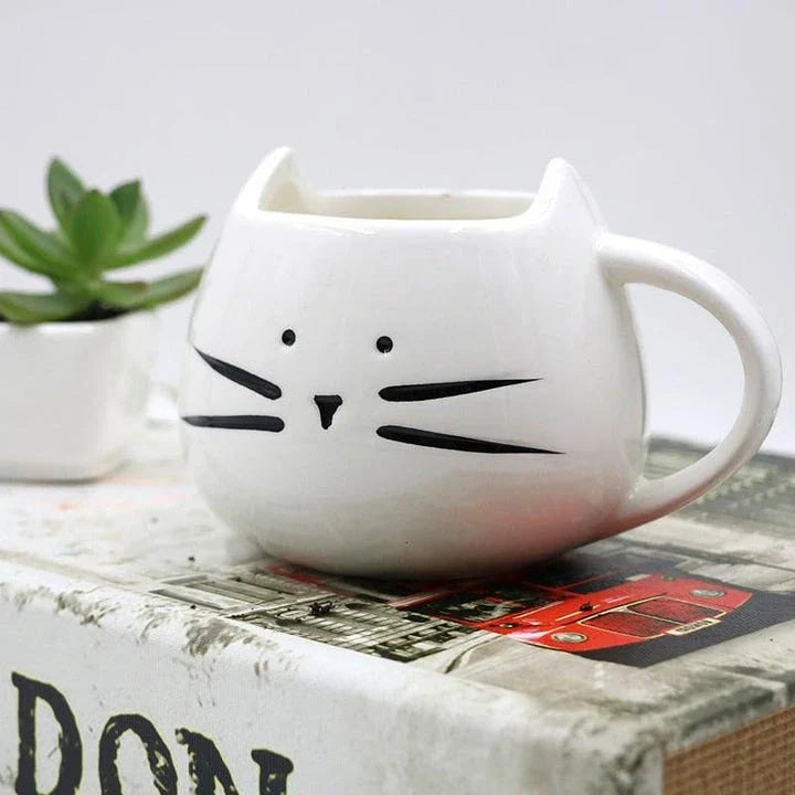 Cartoon cat-shaped ceramic coffee mug with matching stainless steel spoon, a practical and whimsical addition to any morning routine.
