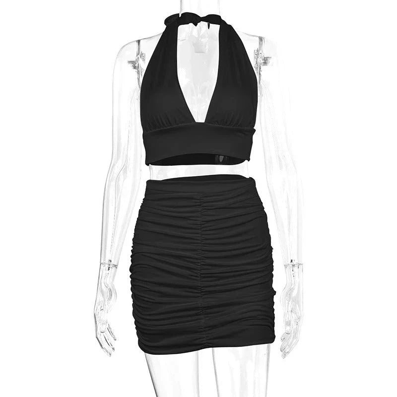 A stylish two-piece dress set featuring a halter-style lace-up top and a pleated hip-covering skirt, available in white, black, and pea green colors.