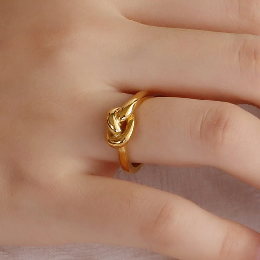 Sleek titanium steel geometric love knot ring in golden and rose gold colours, showcasing a modern and sophisticated design