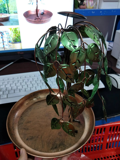 Aged copper Tree of Life electric fountain with cascading waterfall in a lush garden setting