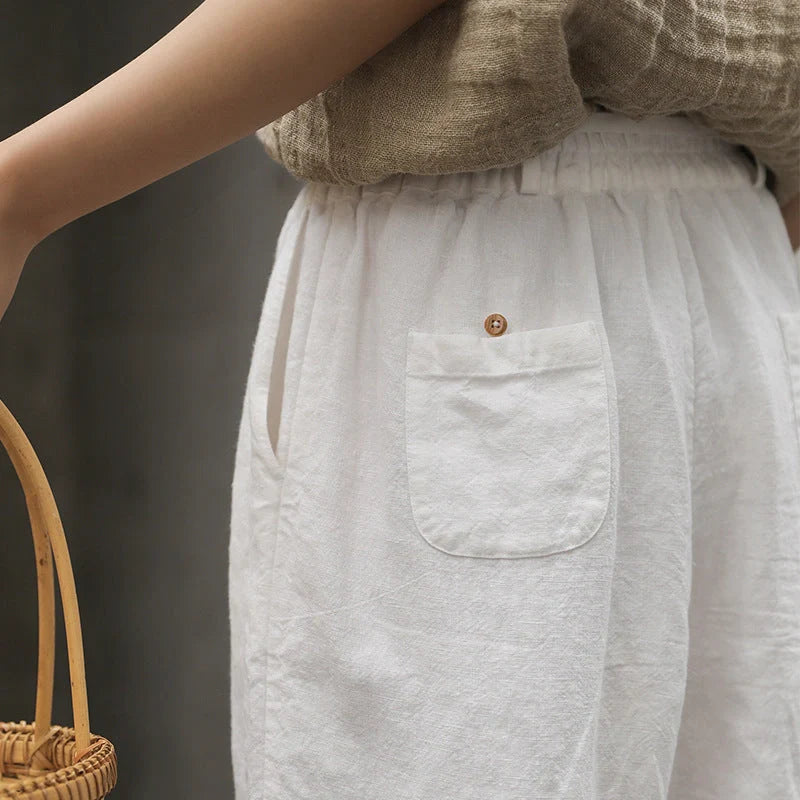 Elegant white linen trousers with a relaxed, artistic silhouette and cropped length