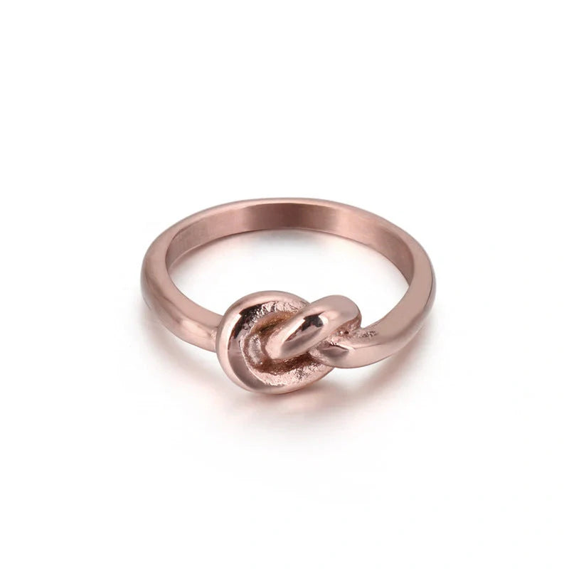 Sleek titanium steel geometric love knot ring in golden and rose gold colours, showcasing a modern and sophisticated design