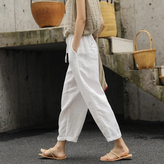 Elegant white linen trousers with a relaxed, artistic silhouette and cropped length