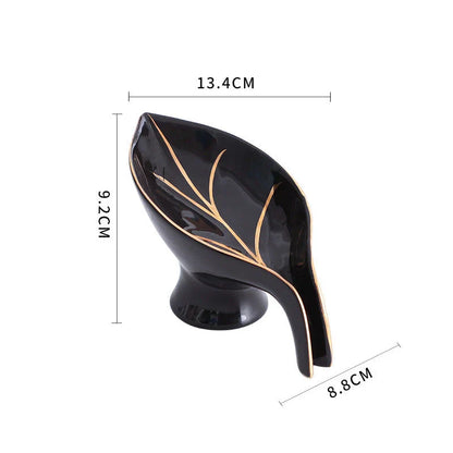 Elegant ceramic soap dish with leaf-shaped design, suction cup base, and drainage holes for bathroom storage and decor