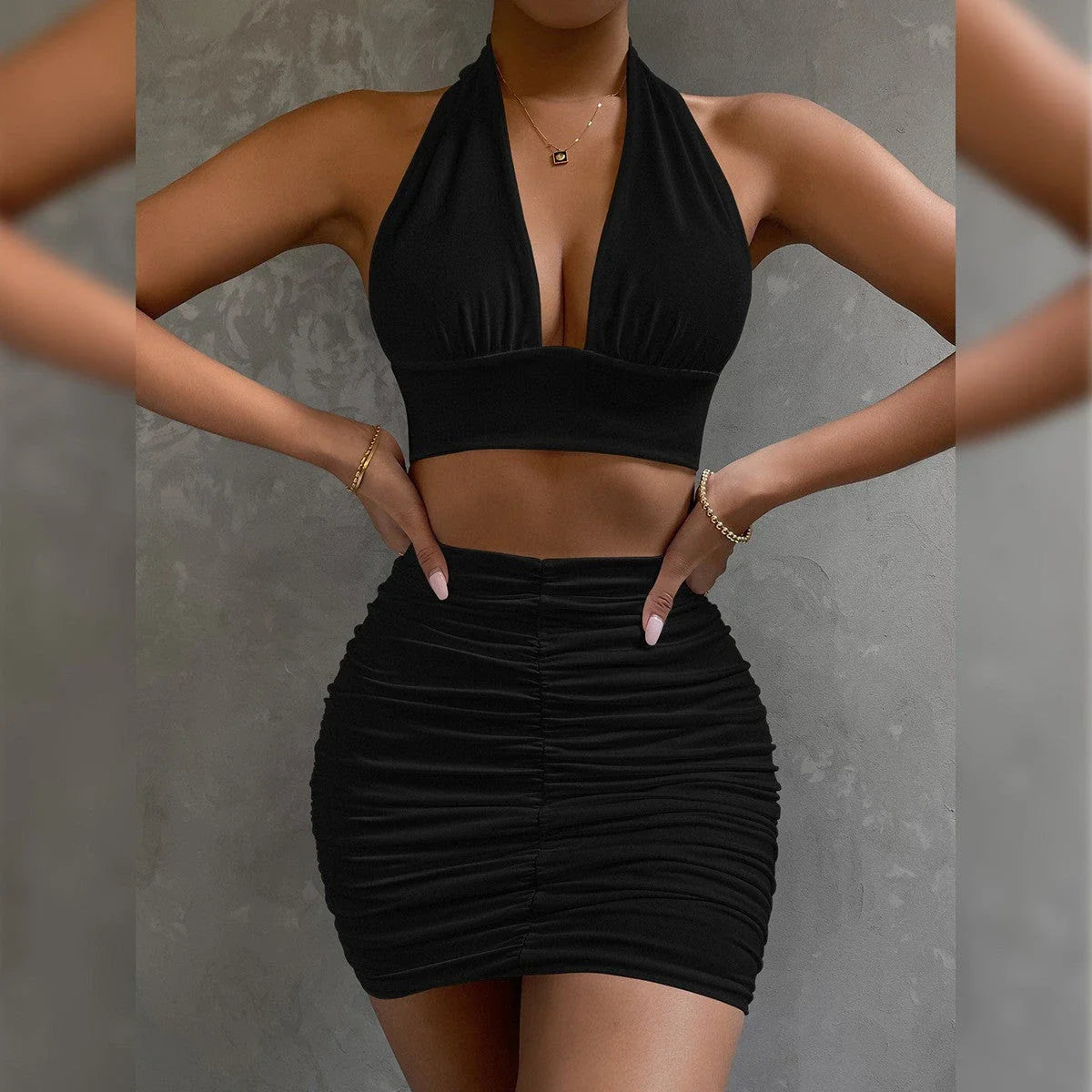 A stylish two-piece dress set featuring a halter-style lace-up top and a pleated hip-covering skirt, available in white, black, and pea green colors.