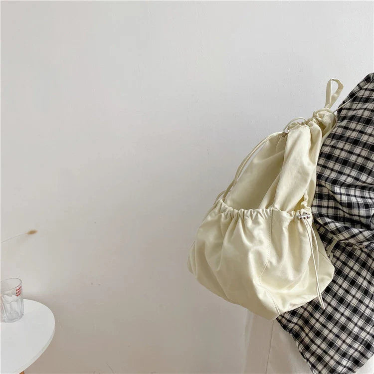 A stylish drawstring bucket bag in white, black, or brown colour options, featuring a spacious interior and adjustable closure for modern British women.