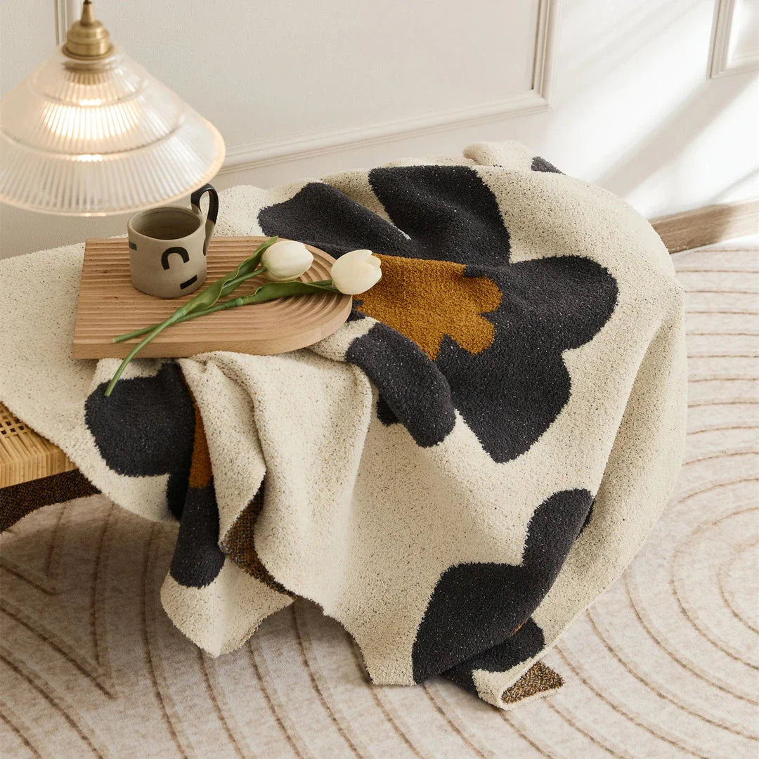 Cosy floral knitted throw blanket in red, grey, and orange colours for year-round comfort and style