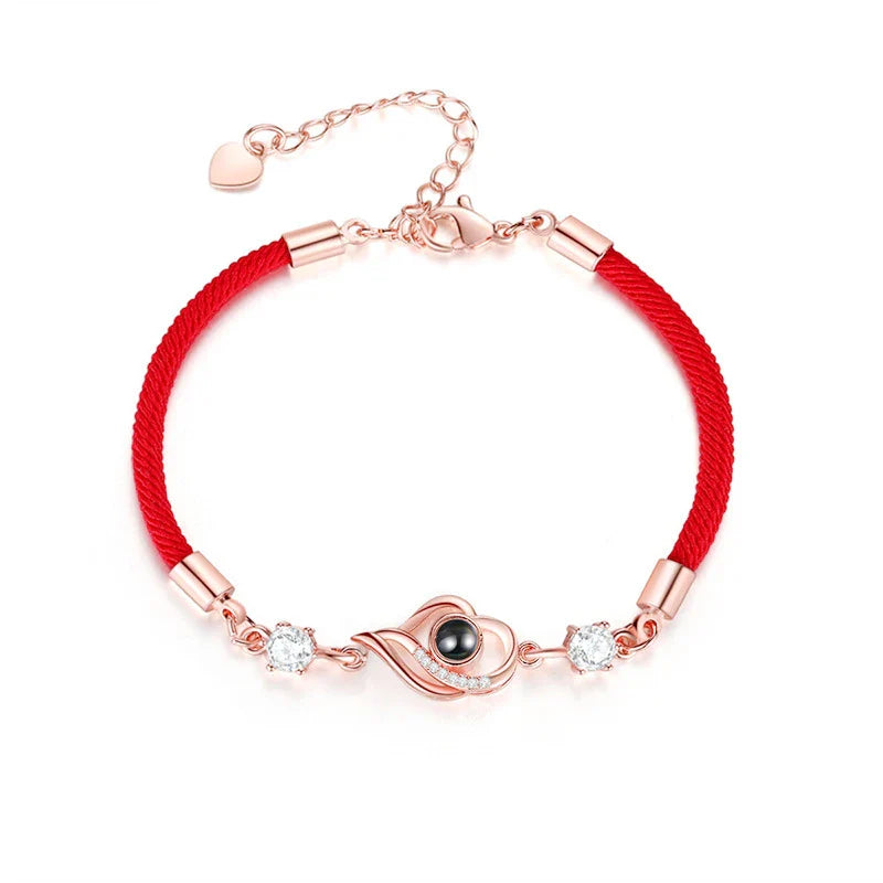 A rose gold or platinum plated copper charm bracelet featuring the phrase 'I Love You' inscribed in 100 languages.