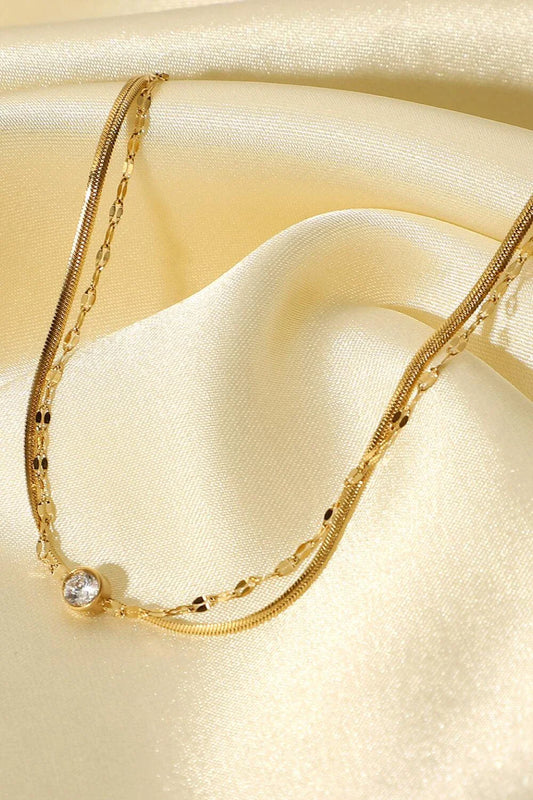 Close-up of a gold-coloured double-layered bracelet with sparkling rhinestones, on a white background.