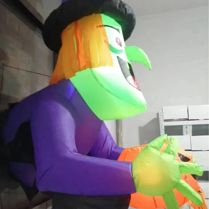 Inflatable Halloween witch decoration holding a spooky pumpkin, set up in a garden or outdoor space