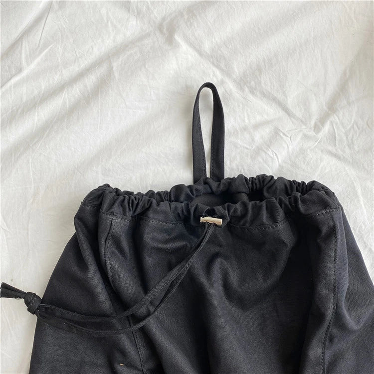 A stylish drawstring bucket bag in white, black, or brown colour options, featuring a spacious interior and adjustable closure for modern British women.