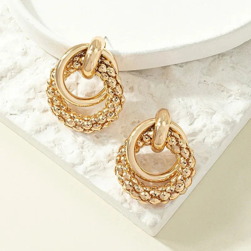 Exquisite gold twist dangle earrings with an intricate geometric design, a bold statement of modern elegance for fashion-forward women.