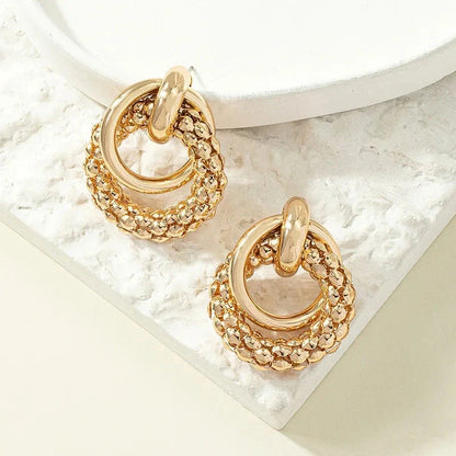 Exquisite gold twist dangle earrings with an intricate geometric design, a bold statement of modern elegance for fashion-forward women.